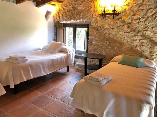 a bedroom with two beds and a stone wall at Aricus Rural: Cal Tià in Girona