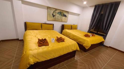 two beds in a room with yellow sheets at White Rose Guesthouse in Koh Rong Island