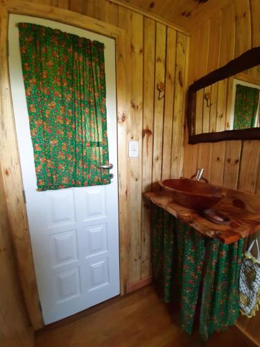 a bathroom with a white door and a sink at Chalé Refúgio das Águas in Urupema