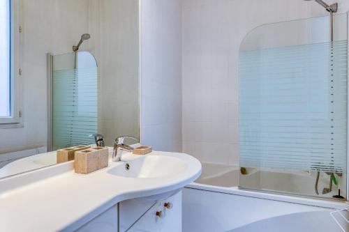 a white bathroom with a sink and a mirror at Dans les arbres à Montmartre in Paris