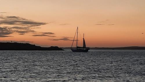 a sail boat in the water at sunset at Smartie Box in Langebaan
