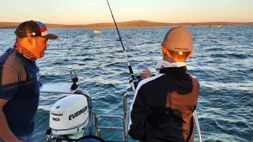 two men fishing on a boat in the water at Smartie Box in Langebaan