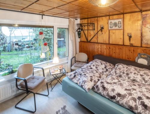 a bedroom with a bed and chairs and a window at Wohnen im Eulengarten in Oranienburg
