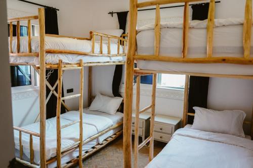 Dar Sultana Guesthouse Surf Morocco في تمراغت: سريرين بطابقين في غرفة مع سريرين أصغر