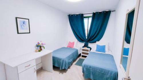 a bedroom with two beds and a desk and a window at Paraíso Para Todos in Mogán