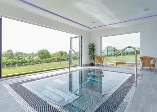 a swimming pool in a room with large windows at Windmill Retreat in Middlezoy