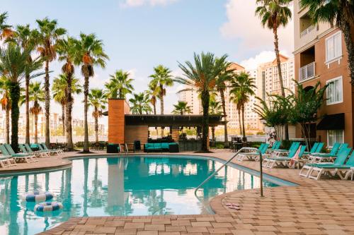 a swimming pool with chairs and palm trees at Sonder at The Point in Orlando