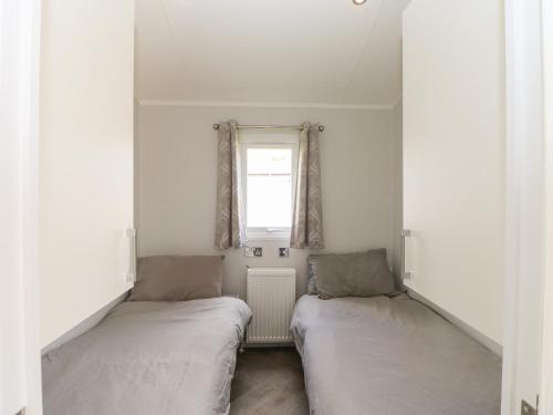 two beds in a small room with a window at Coverdale Large Pod in Yarm