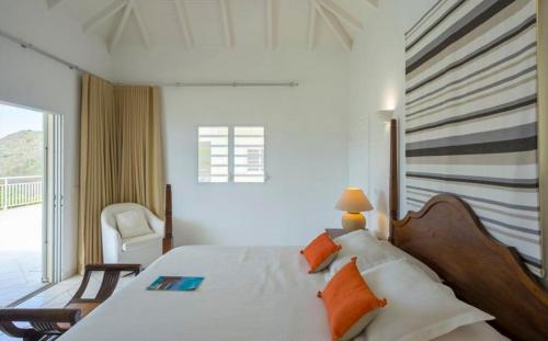 1 dormitorio con 1 cama, 1 silla y 1 ventana en Saint Barth Villa 3, en Saint-Jean