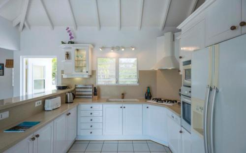 una cocina con armarios blancos y electrodomésticos blancos en Saint Barth Villa 3, en Saint-Jean