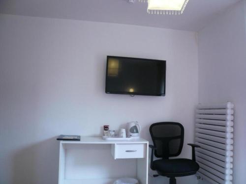 a room with a chair and a tv on the wall at Ardenlea House Hotel B&b in Dyce