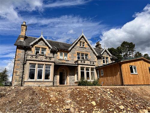 una gran casa de piedra en la parte superior de un campo de tierra en Forces Manor en Kincraig