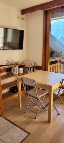 a dining room with a table and chairs and a television at Appartement les 2 Alpes avec vue sur la muzelle in Vénosc