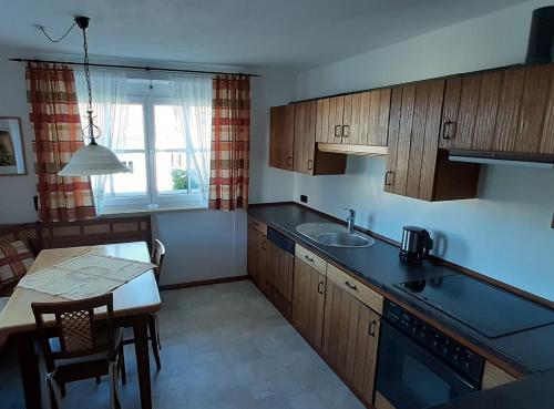 a kitchen with wooden cabinets and a table with a sink at Ferienwohnung Wenzl in Schnaitsee