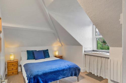 a bedroom with a bed with blue sheets and a window at Finest Retreats - Atherfield Apartments No 8 - Roof Tops in Paignton
