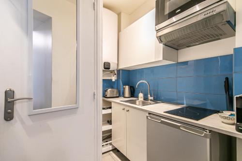 - une petite cuisine avec des placards blancs et du carrelage bleu dans l'établissement MBA Splendide Appart - Parmentier - Paris - Proche Bastille, à Paris