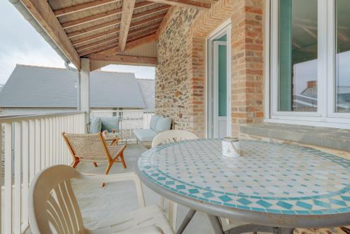 un patio avec une table et des chaises sur un balcon dans l'établissement Côte d'emeraude, à Saint-Benoît-des-Ondes