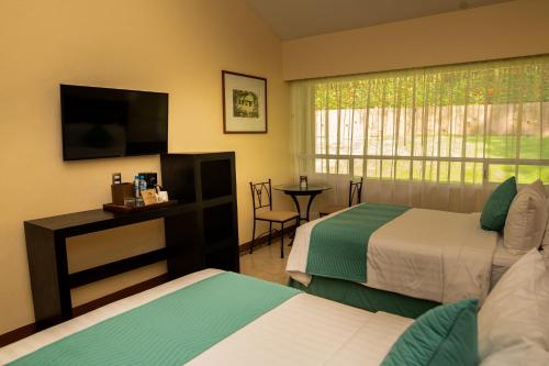 a hotel room with two beds and a television at Hotel Villa Mercedes Palenque in Palenque