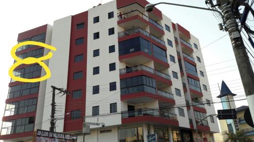 a tall red and white building with a yellow symbol at Apartamentos Ed London, na Av principal a poucos passos das Termas in Piratuba