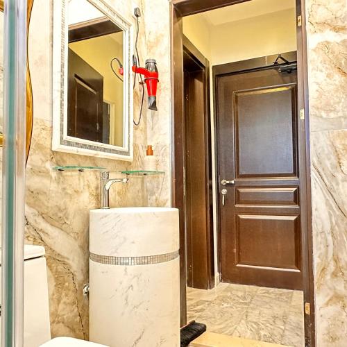 a bathroom with a toilet and a mirror and a door at منتجع اووه يامال البحري في الخيران OOh Yaa Mal in Al Khīrān