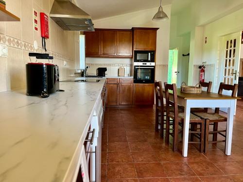 a kitchen with a counter and a table and chairs at Tapada dos Ribeiros in Alpalhão
