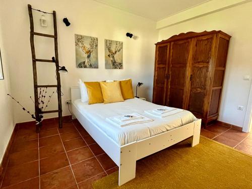 a bedroom with a white bed and a wooden cabinet at Tapada dos Ribeiros in Alpalhão