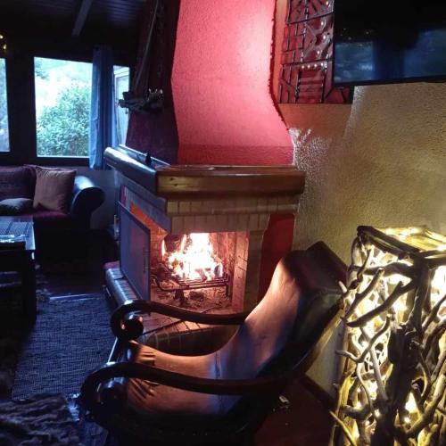 a fireplace in a living room with a chair in front of it at CHALET LE BLANC in Arachova