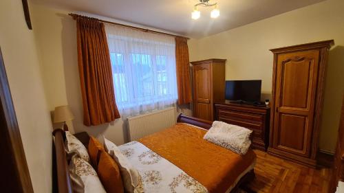 een slaapkamer met een bed, een dressoir en een televisie bij Apartament Bogdan in Gura Humorului