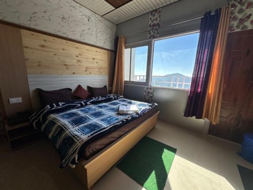 um quarto com uma cama e uma grande janela em Kanatal's Valley View INN em Kanatal