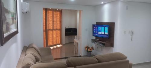 Il comprend un salon doté d'un canapé et d'une télévision à écran plat. dans l'établissement Apartamentos na cobertura - Edifício London, à Piratuba
