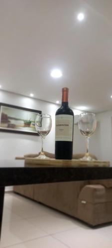 a bottle of wine and two glasses on a table at Apartamentos na cobertura - Edifício London - Com Ar-condicionado em todos os cômodos in Piratuba