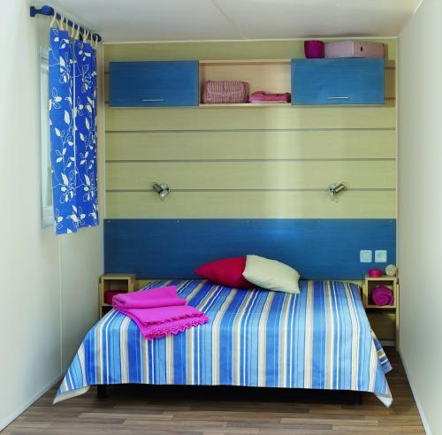 a childs bedroom with a striped bed with pink towels at Camping Paradis Le Zagarella in Saint-Jean-de-Monts