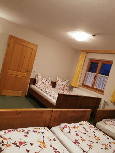 a room with three beds and a door and two windows at Gästehaus Bonholz in Stummerberg