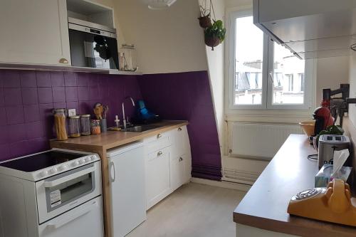 a kitchen with white cabinets and a purple wall at Luxurious Apartment Near Parc André Citröen in Paris