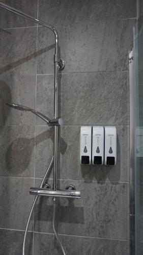 eine Dusche mit einer Glastür mit zwei Flaschen in der Unterkunft Aqua Dream Luxury Apartment-Coyles Place at Portland 88 in Belfast