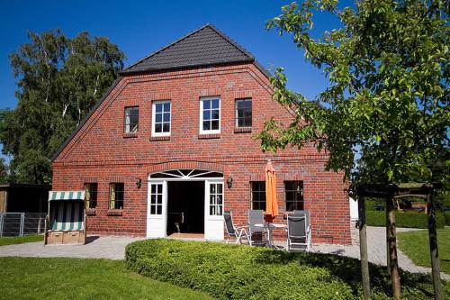 une grange en briques rouges avec deux chaises devant elle dans l'établissement Karl Sonnenstrahl 9242VI - Fehmarn, à Fehmarn