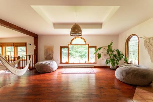 sala de estar con suelo de madera y ventana grande en Auberge Yoga Salamandre en Lac-Brome