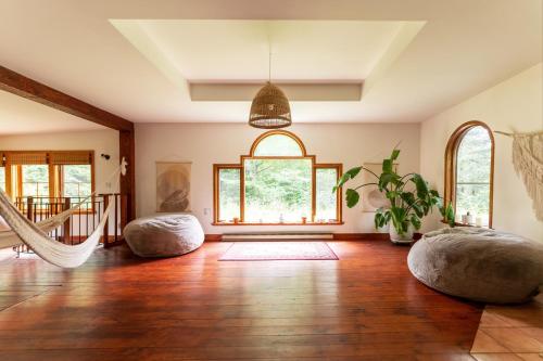 a living room with wooden floors and a large window at Auberge Yoga Salamandre in Lac-Brome