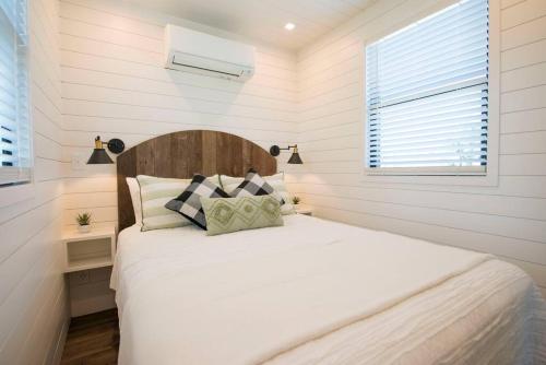 een slaapkamer met een bed met witte lakens en een raam bij The Pecan Grove Container Home 15 min to Magnolia in Bellmead