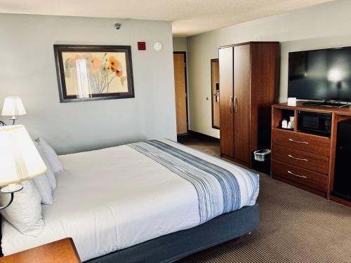 ein Hotelzimmer mit einem Bett und einem Flachbild-TV in der Unterkunft AmericInn by Wyndham Stillwater in Stillwater