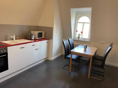 uma cozinha com uma mesa e cadeiras e um micro-ondas em Kleine Wohnung in schöner Villa em Meerane