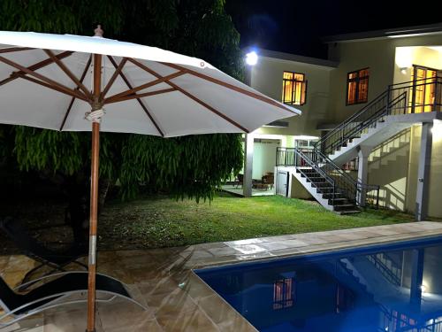 a white umbrella sitting next to a swimming pool at Villa Tameva in Flic-en-Flac