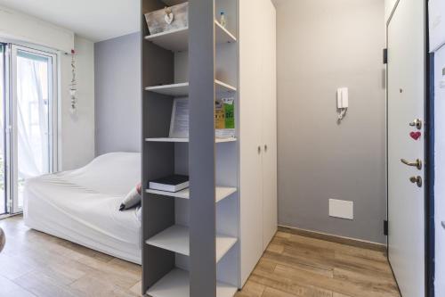 Appartamento-Sanremo my Home Free parking-Wi-fi في سانريمو: غرفة مع رف للكتب بجوار سرير