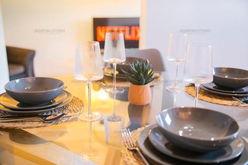 una mesa con platos y copas de vino. en Riverside Drive Apartment - Grampian Lettings Ltd, en Aberdeen