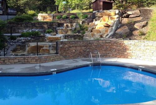 a swimming pool with a waterfall in a backyard at Spacious Smokies Cabin - Hot Tub with Mountain Views in Gatlinburg