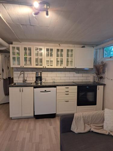 a kitchen with white cabinets and a couch in a room at Lägenhet Huskvarna in Jönköping