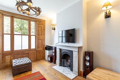 een woonkamer met een open haard en een televisie bij The Artist's House Alma Street in Londen