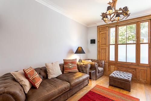 un soggiorno con divano marrone e sedia di The Artist's House Alma Street a Londra
