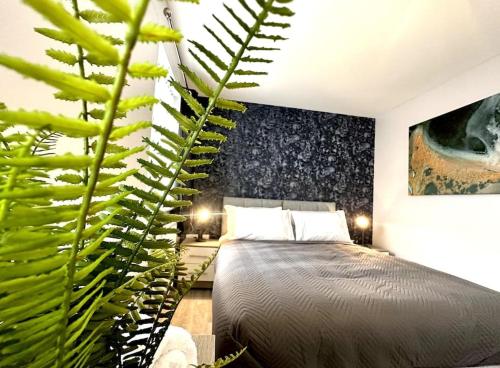 a bedroom with a bed and a large green plant at Riverside View by Blue Skies Stays in Middlesbrough