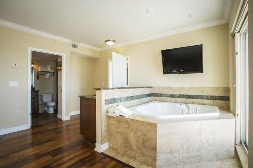 a large bathroom with a tub and a tv on the wall at Crystal Palms Beach Resort in St. Pete Beach